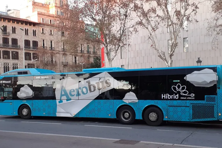 Bus Aerobús hybride bleu et blanc, livrée actuelle, longeant la place de Catalunya