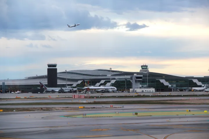Il Terminal 1 dell'aeroporto di Barcellona-El Prat, la sua torre di controllo e un aereo in decollo
