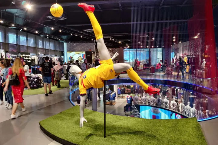 Eine Skulptur eines Fußballspielers in Aktion dominiert die Regale und Besucher des Barça-Shops.