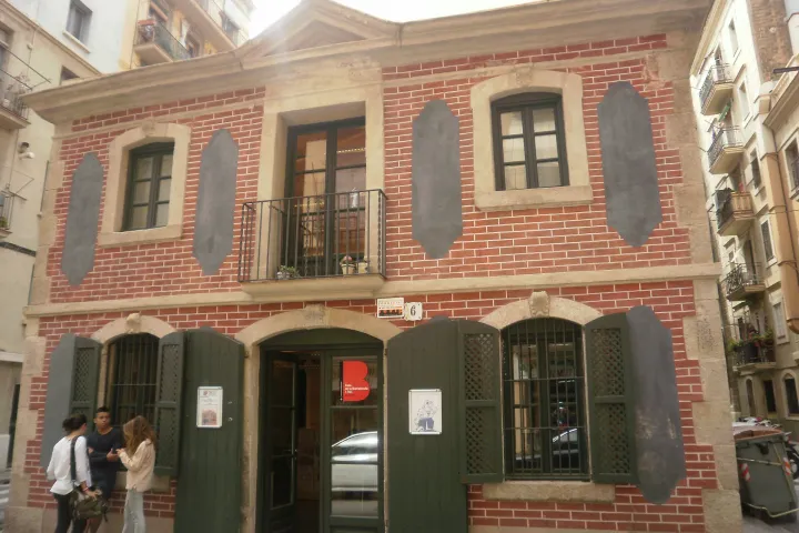 A Casa de la Barceloneta de 1761, uma casa baixa de tijolos com venezianas verdes, em uma rua estreita do bairro