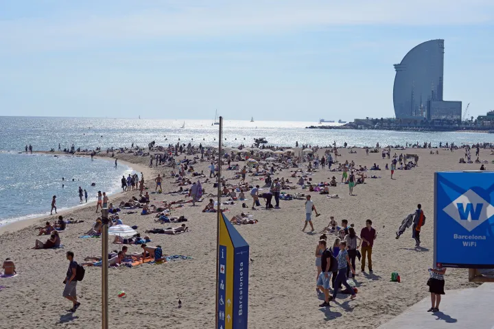 Os banhistas da praia de Sant Miquel, com a vela do hotel W no final da orla