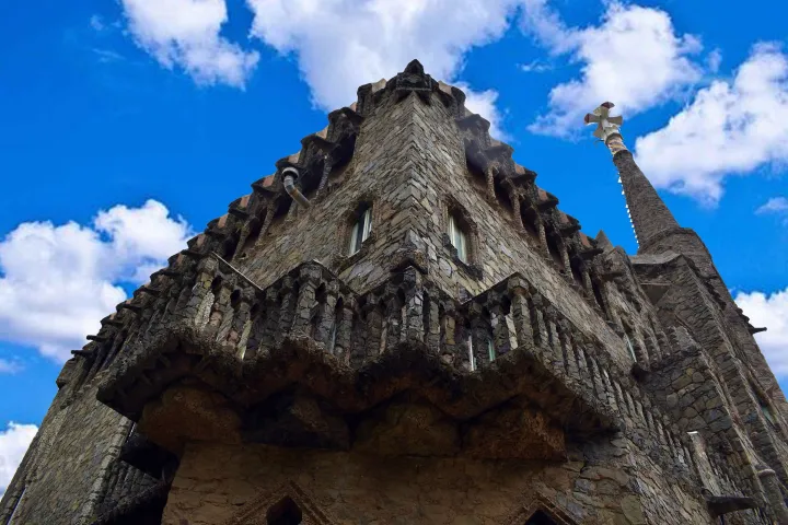 La fachada de piedra de Torre Bellesguard, sus almenas y sus ventanas verticales vistas desde abajo