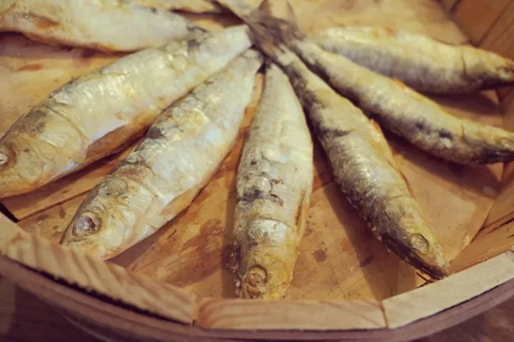 Whole small fish arranged in a fan shape on a plate.