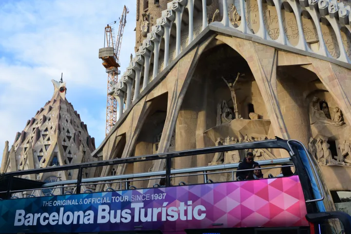 Um Ônibus Turístico de dois andares passa em frente à fachada da Natividade da Sagrada Família