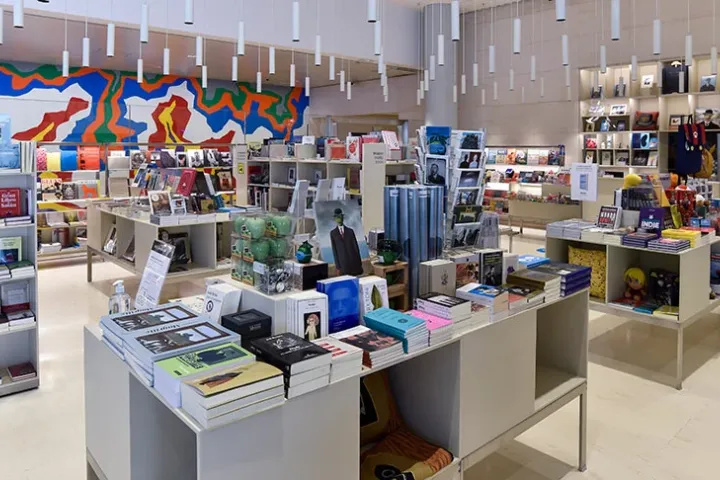 The CaixaForum bookstore, its tables filled with art books and displays, in front of a colorful mural