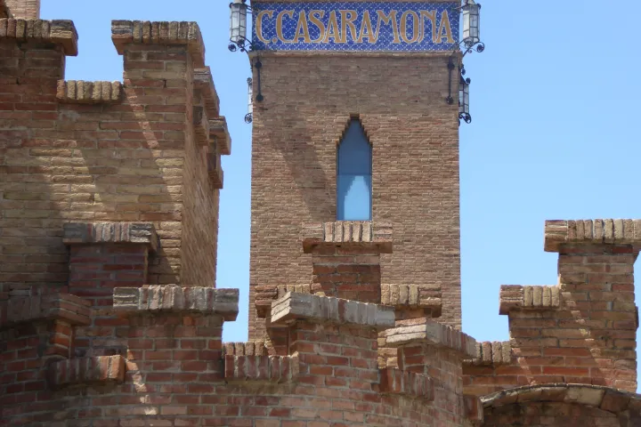 The crenellated brick rooftops of the former Casaramona factory and its tower with the ceramic sign