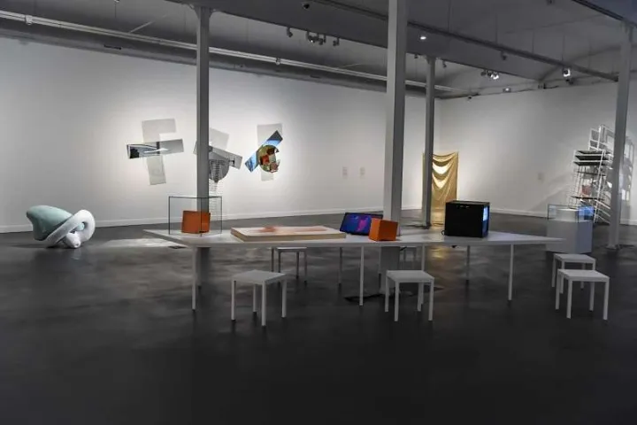 A white room at CaixaForum where design objects are placed on low tables, in front of artworks hanging on the wall