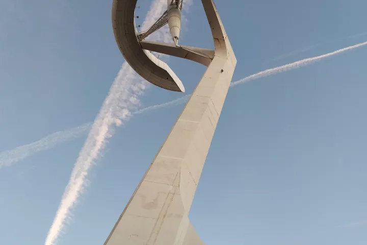 Il lungo fusto bianco inclinato della Torre di Calatrava visto dalla base, con l'insegna Telefónica