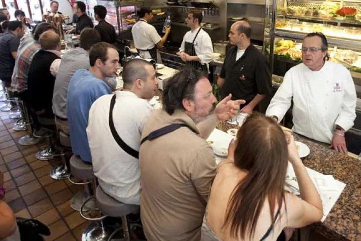 Guests seated side by side at the counter facing the chefs and the open kitchen.
