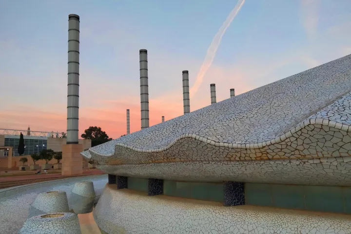 La base ondulata della torre, coperta di trencadís bianco, davanti alle colonne dell'esplanade al tramonto