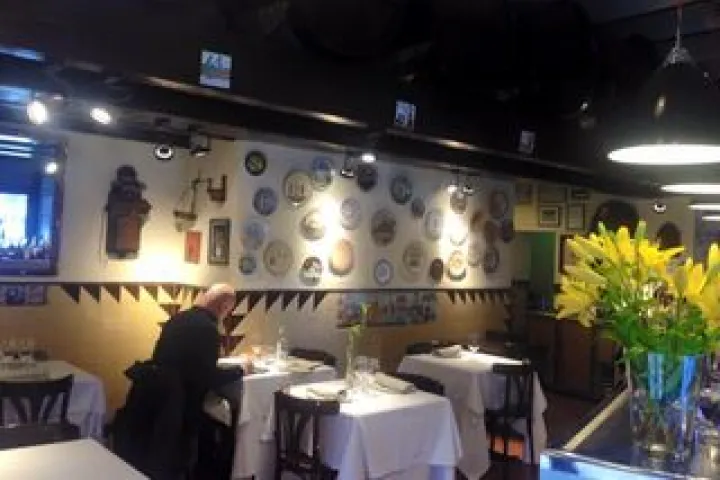Tables set and wall decorated with plates in the dining room of Can Pineda.