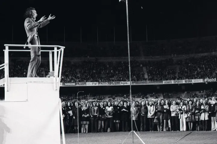 Oriol Martorell dirigiert die Chorsänger, die sich auf dem Rasen des Camp Nou versammelt haben, für die erste Aufführung des Cant del Barça im Jahr 1974.