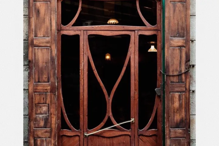 Geschnitzte Holztür von Casa Almirall unter ihrem grünen Schild.