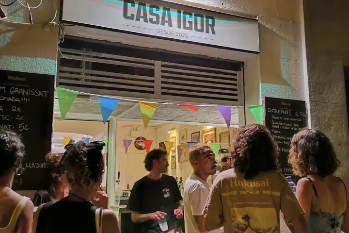 Customers gathered in front of the counter open to the street, under the Casa Igor sign.