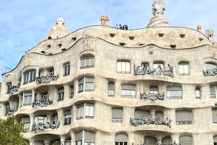 Die wellenförmige Steinfassade des Casa Milà und seine schmiedeeisernen Balkone, mit den Schornsteinen der Dachterrasse