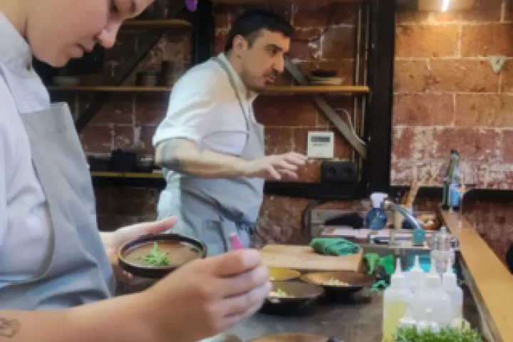 Chefs prepare plates in front of customers seated at the counter.