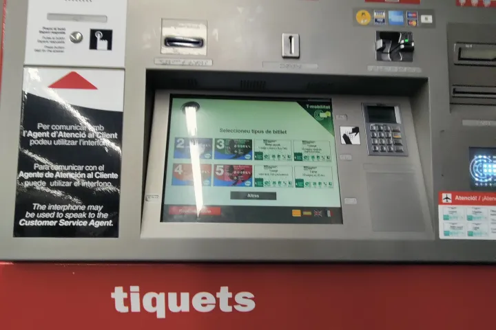 Distributeur rouge de tickets du métro de Barcelone, avec écran tactile et fente de retrait des billets