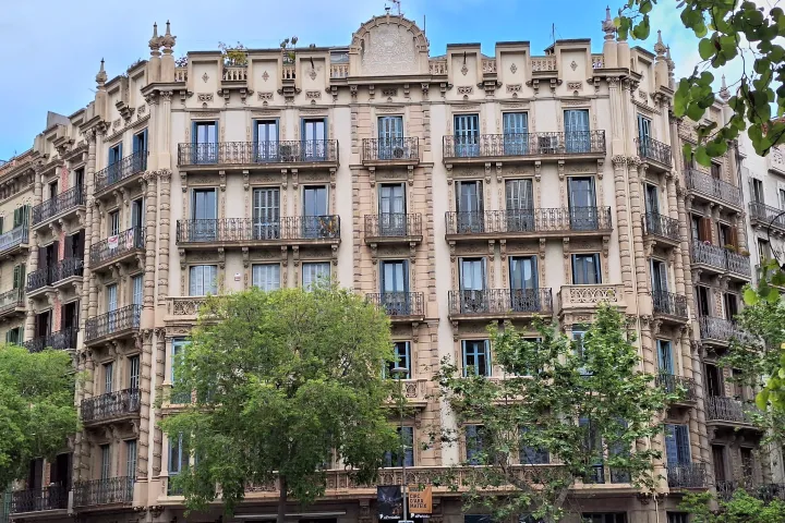 A fachada da Casa Sabata na esquina do Carrer d'Enric Granados, suas varandas de ferro forjado e os plátanos da rua