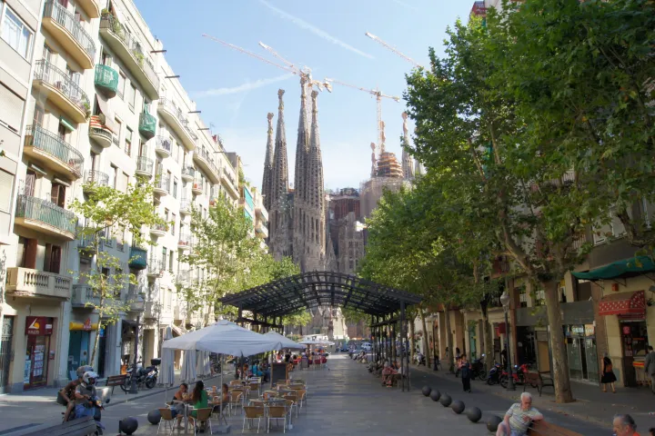 As cafeterias com terraço da Avinguda de Gaudí, seus postes de luz modernistas e as torres da Sagrada Família no final da avenida