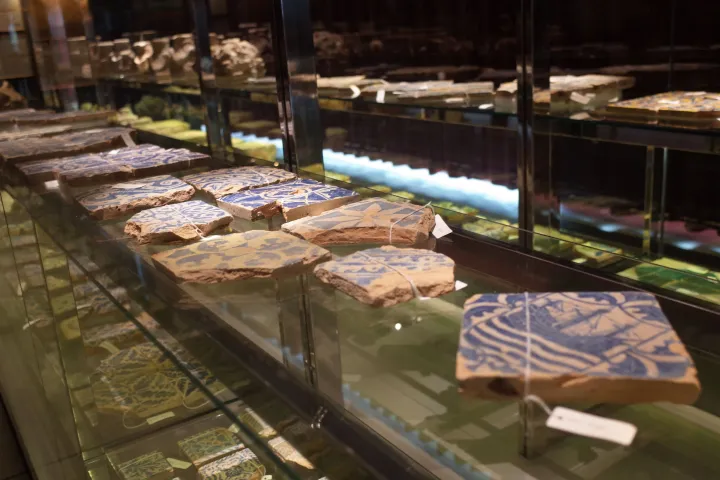 Blaue und weiße Keramikfliesen, die bei den Ausgrabungen der Stätte gefunden wurden, in einer Vitrine ausgestellt