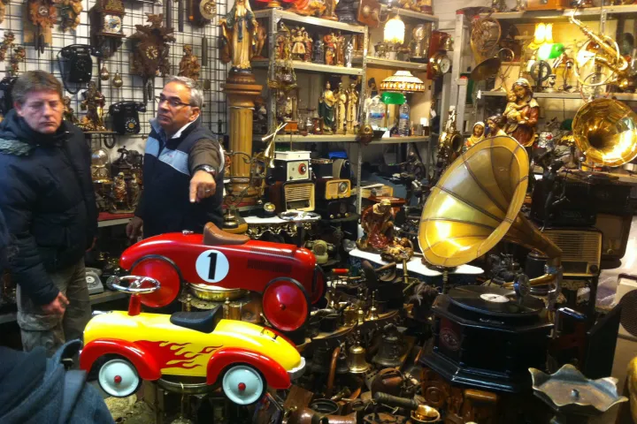 A stall at the Encants brimming with antique items, horn gramophones, and a red pedal car