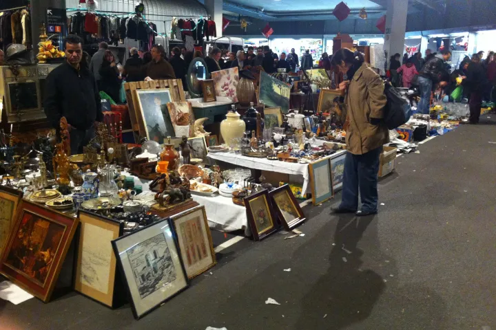 Framed paintings, mirrors, and antique vases placed directly on the ground at a stall in the Encants