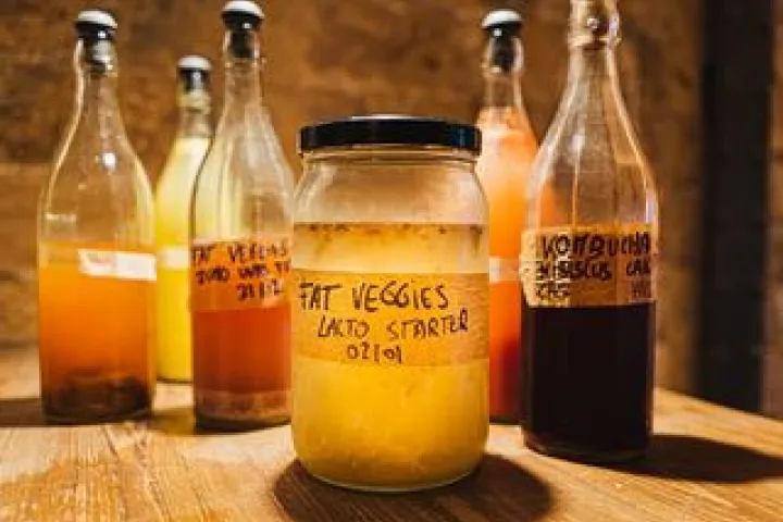 Bottles and jar of fermented preparations from Fat Veggies on a wooden table.
