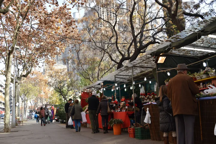 Besucher schlendern zwischen den Ständen der Fira de Nadal unter den herbstlichen Platanen