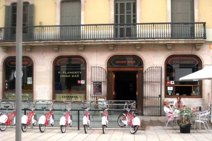 Fassade des Flaherty’s Pub mit einer Fahrradstation und einer Terrasse vor dem Eingang.