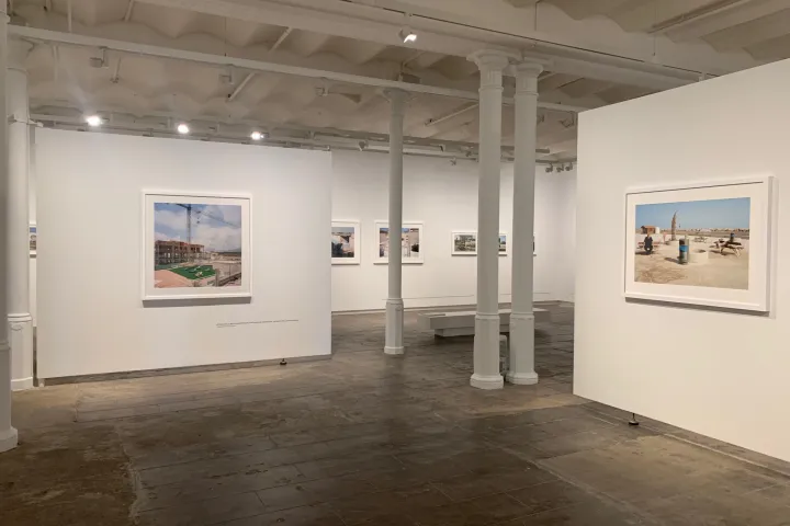 Fotografías enmarcadas colgadas en paredes blancas, entre las columnas de hierro fundido de un antiguo local industrial