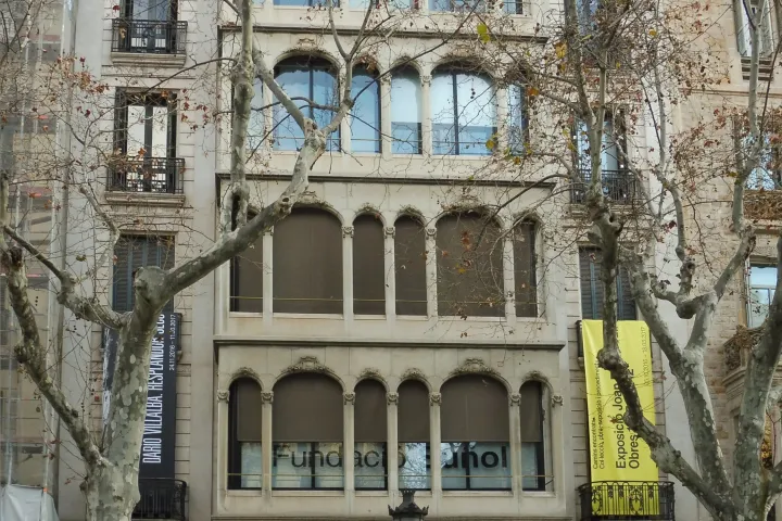 Die Fassade des Gebäudes am Passeig de Gràcia, das die Fundació Suñol beherbergt, hinter den Platanen