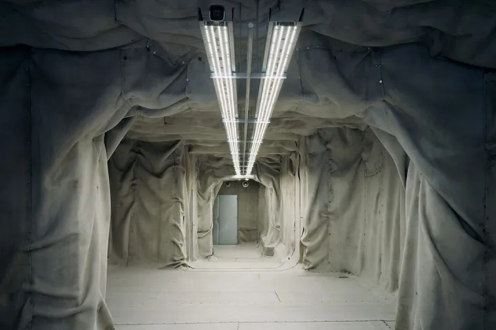 Interior de Gimaguas con paredes grises escultóricas e iluminación suspendida.