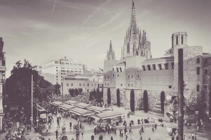 Vista dall'alto dell'Avinguda de la Catedral: la fila di bancarelle del Mercato Gotico, la folla, la muraglia romana e le guglie della cattedrale