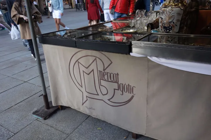 Il telone di uno stand del Mercato Gotico con il logo del mercato, davanti a una vetrina di oggetti antichi