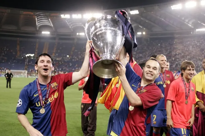 Lionel Messi und Andrés Iniesta heben gemeinsam mit ihren Teamkollegen auf dem Spielfeld 2009 die Champions-League-Trophäe.