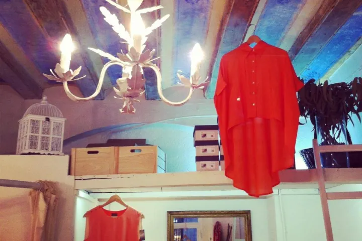 Ropa roja colgada bajo una lámpara de araña en la tienda Ivori.