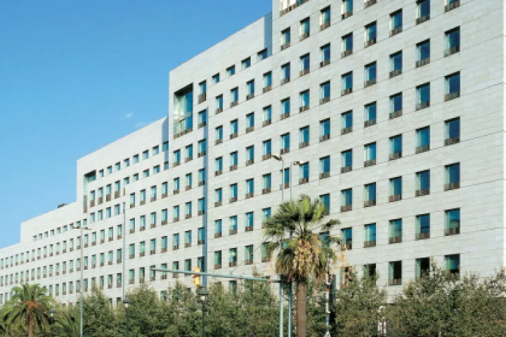 Larga fachada de L'illa Diagonal con sus ventanas alineadas y sus palmeras.