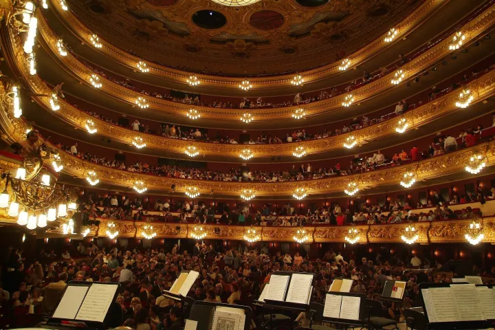 La salle du Liceu en fer à cheval, ses rangées de loges illuminées et les pupitres de l'orchestre au premier plan