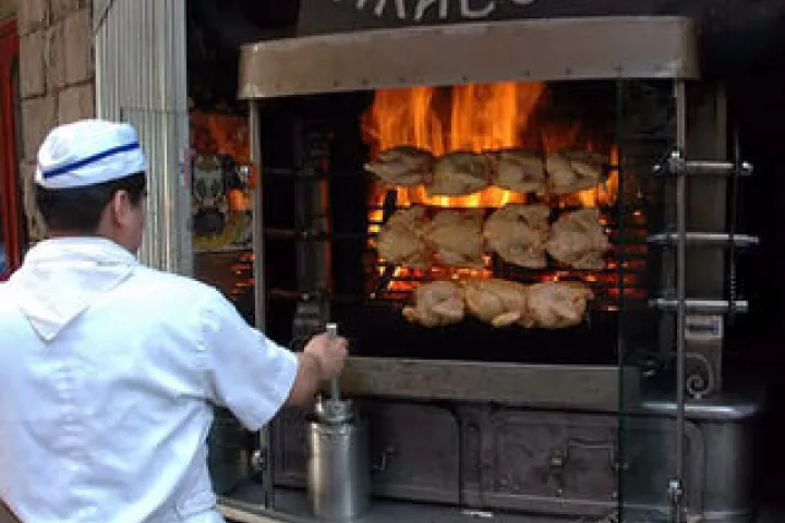 A chef in front of the rotisserie and the golden chickens at Los Caracoles.