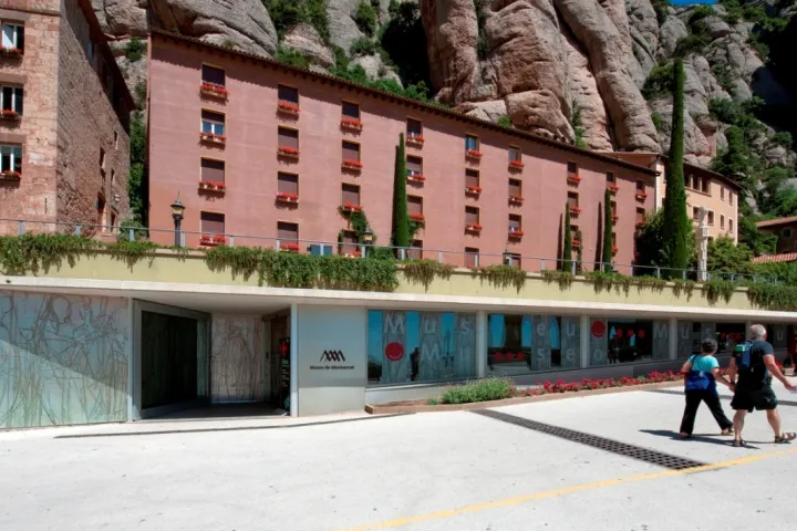 A entrada envidraçada do museu de Montserrat, aos pés dos edifícios do santuário e das paredes rochosas.