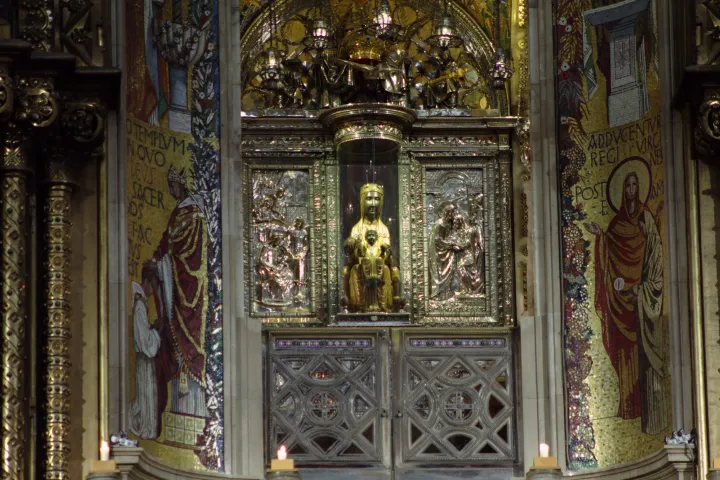 A estátua da Moreneta e do Menino em seu trono, cercada pela decoração dourada e mosaicos da basílica.