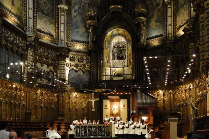 O coro da Escolania canta diante do altar, sob as decorações douradas da basílica de Montserrat.