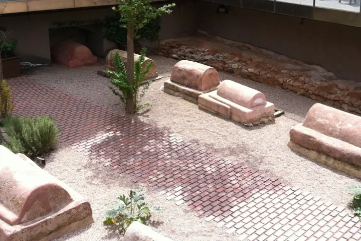 Roman sarcophagi lined up in a sunken garden at the site of the Roman Sepulchral Way