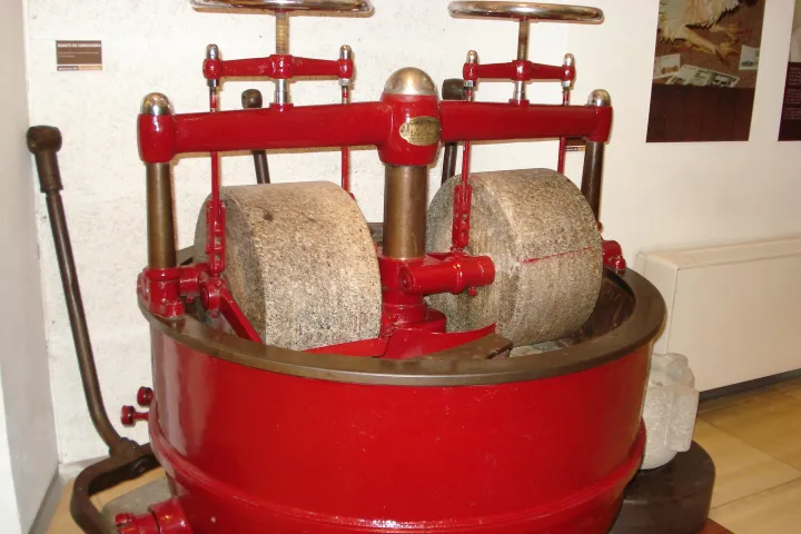 Una concha de cilindros de granito pintada de rojo, antigua máquina utilizada para moler y refinar el chocolate