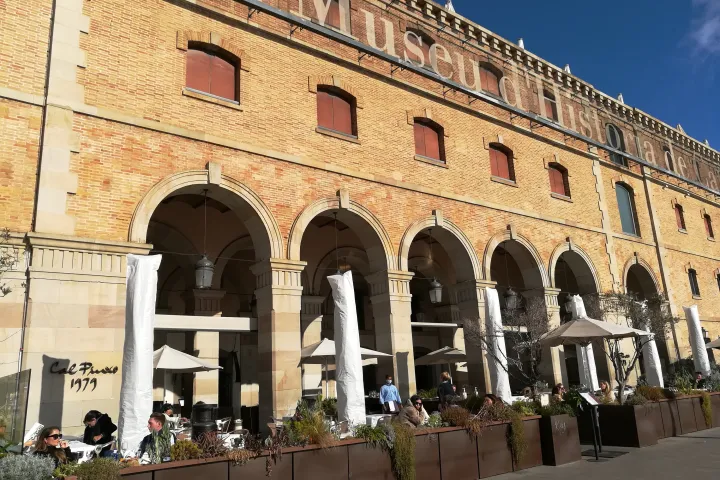 La façade en brique du Palau de Mar, ses arcades et le nom du musée en grandes lettres, avec les terrasses en contrebas