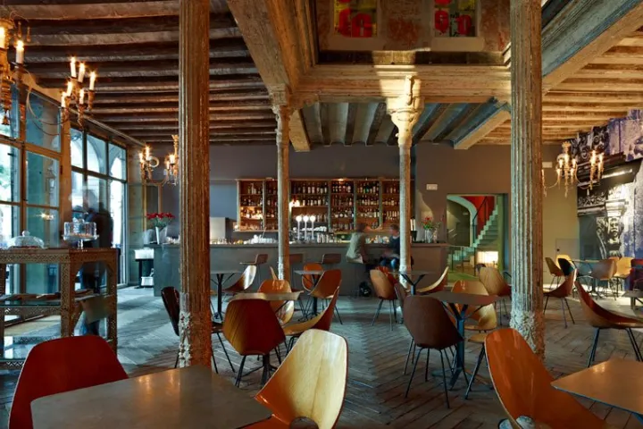Ocaña-Saal mit Tischen, bunten Stühlen, Säulen und dekorierten Decken.