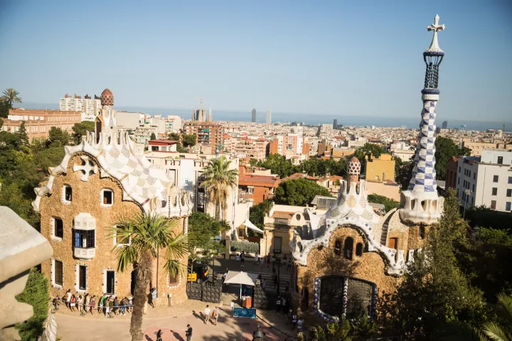 I due padiglioni d'ingresso del Parco Güell e i loro tetti in trencadís, visti dalla terrazza, con Barcellona e il mare all'orizzonte