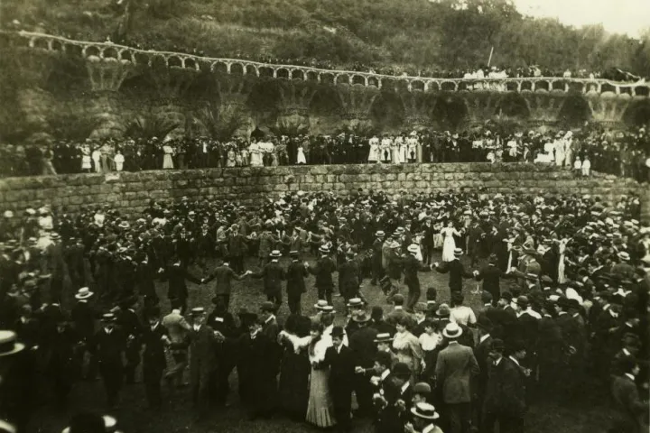 Una folla che danza la sardana sulla piazza della Natura del Parc Güell nel 1906, ai piedi della panchina ondulata