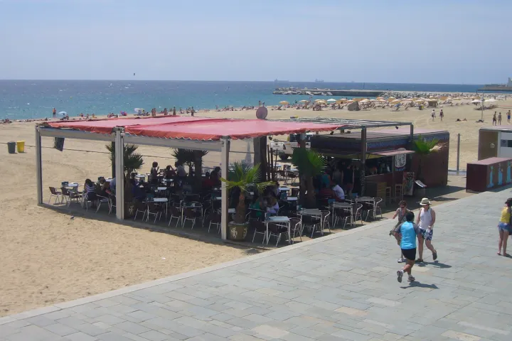 The shaded terrace of a chiringuito on Bogatell Beach, with the sea in the background