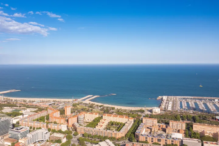 A praia de Nova Icària vista do alto, com a marina do Porto Olímpico e as torres do Hotel Arts e da Torre Mapfre ao fundo